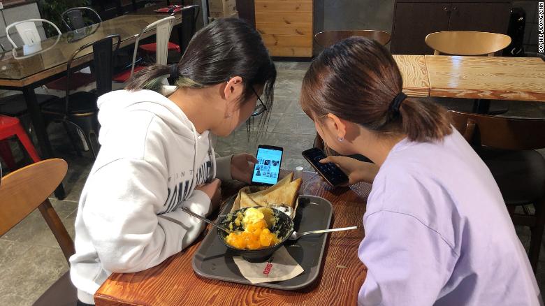 Yoo Chae-rin (left) shows photos of various hairstyles to her friend Kim Hyo-min  (right) in a coffee shop near Seoul in September 2019.