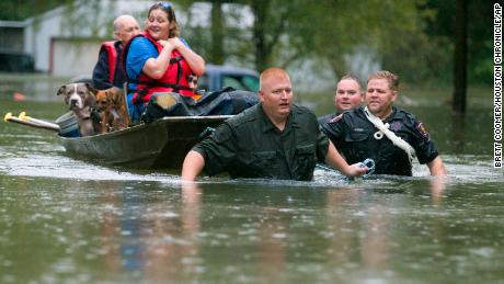 Police pull a boat carrying residents Thursday from their flooded neighborhood in Splendora, Texas.