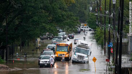 A man tries to direct a school bus Thursday on a flooded road in Houston.