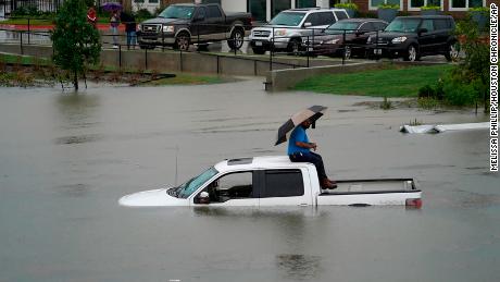 A man sits on top of a truck on a flooded road Thursday in Houston. Members of the Houston Fire Department gave him a life jacket and walked him to dry land.