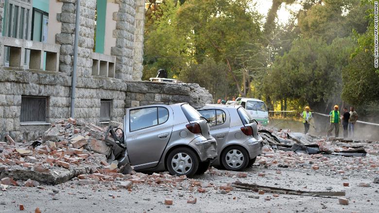 Vehicles are crushed as emergency services workers clear the ruins of a collapsed building roof in Tirana, Albania, after an earthquake.