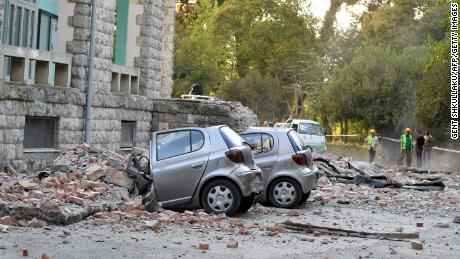 Vehicles are crushed as emergency services workers clear the ruins of a collapsed building roof in Tirana, Albania, after an earthquake.
