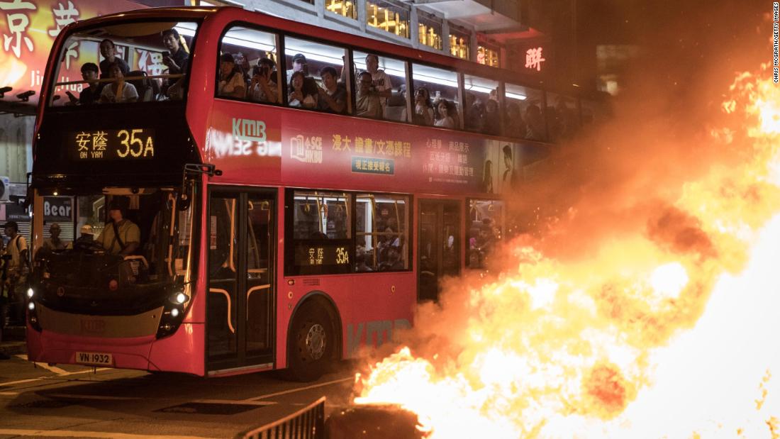 Bus passengers look at a burning barricade lit by pro-democracy protesters in front of the Mong Kok police station on Sunday, September 22.