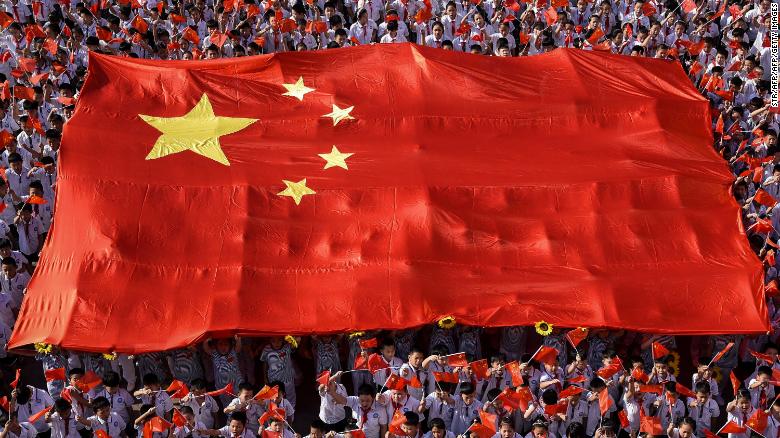 This photo taken on September 1, 2019, shows elementary school students waving national flags as they sing a patriotic song on the first day of the new semester in Handan in China&#39;s northern Hebei province.