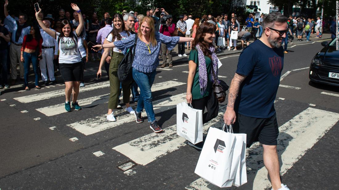 Beatles fans walk across the Abbey Road crossing in London on August 8, 2019, to mark the 50th anniversary of the eponymous album's release. 