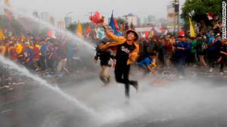 Student protesters hurl objects as they are sprayed by a police water cannon truck during a protest outside the parliament in Jakarta, Indonesia, on September 24, 2019. 