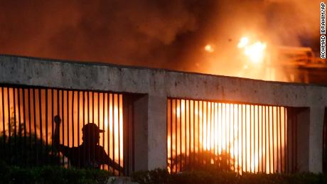 Student protesters throw stones at riot police as a gate burns in the background during a protest outside the parliament in Jakarta, Indonesia, on September 24, 2019. 