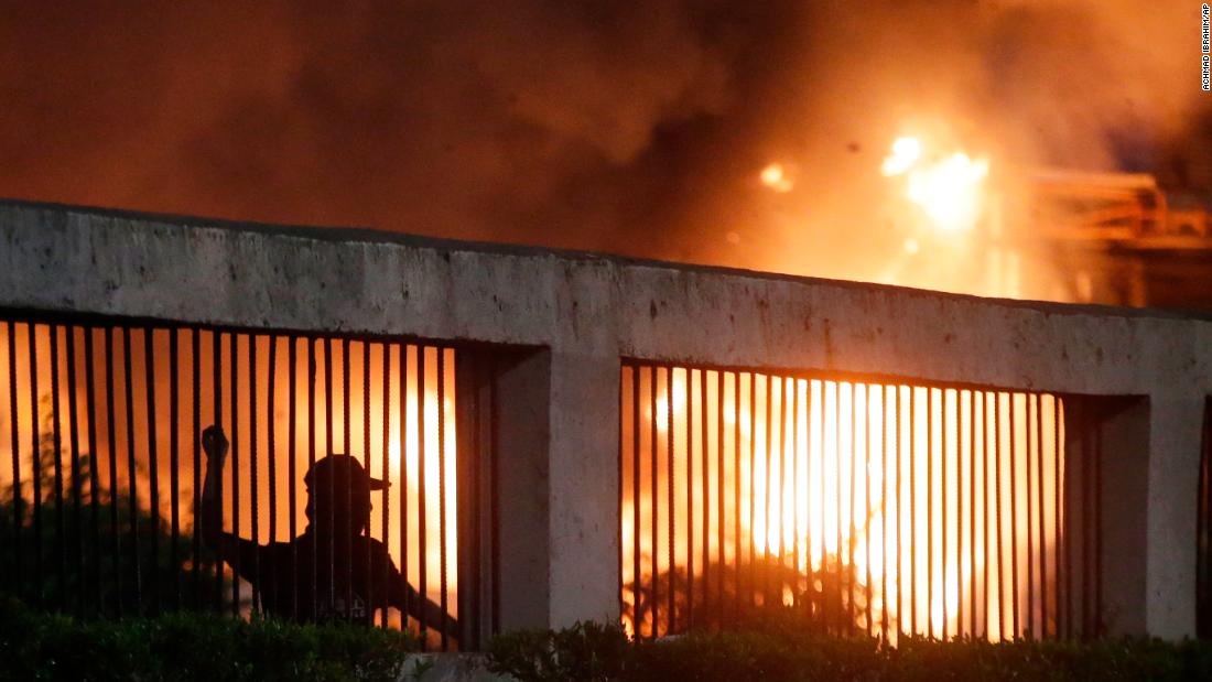 Student protesters throw stones at riot police as a gate burns in the background during a protest outside the parliament in Jakarta, Indonesia, on September 24, 2019. 