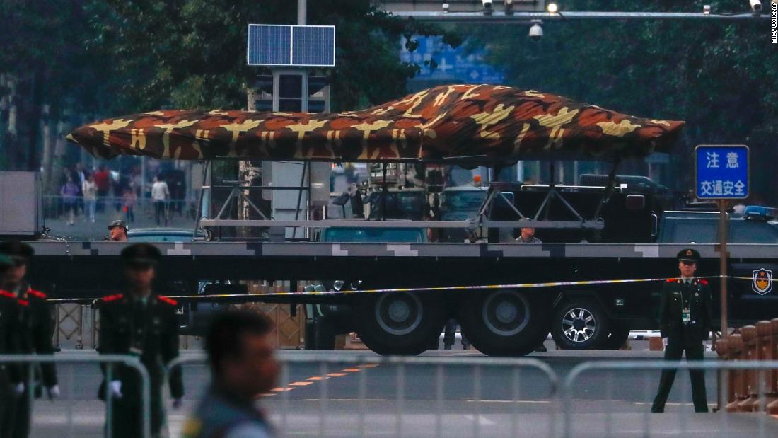 Chinese paramilitary policemen stand guard as a Chinese military vehicle possibly carrying a drone participates in an October 1 parade rehearsal.