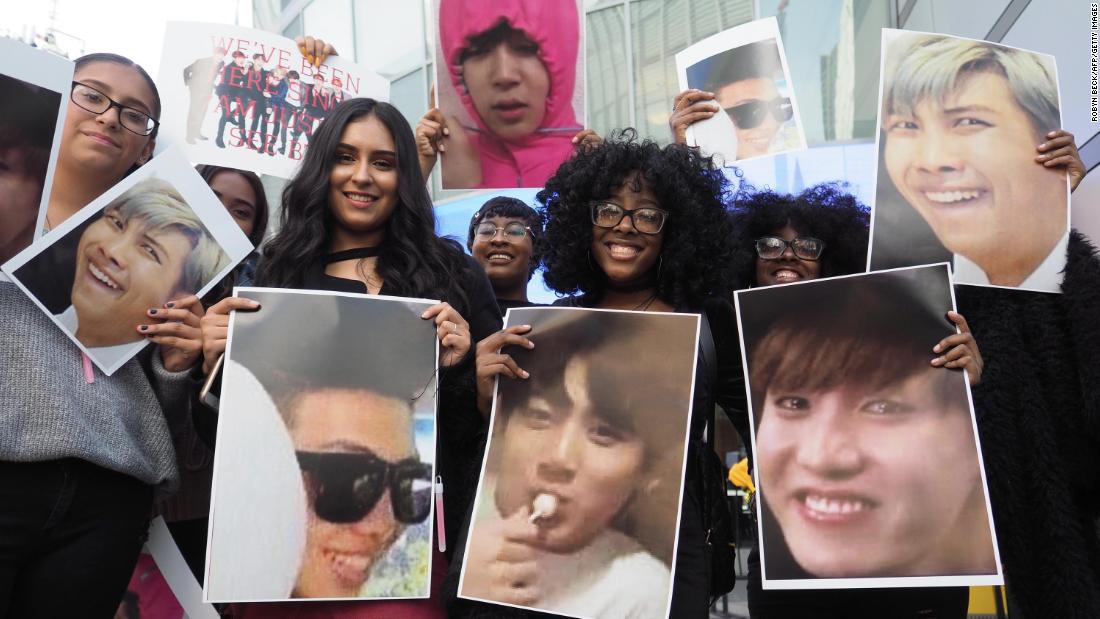 Fans of the Korean boy band group BTS pose with photos of their idols outside the 2017 American Music Awards, November 19, 2017 in Los Angeles, California.