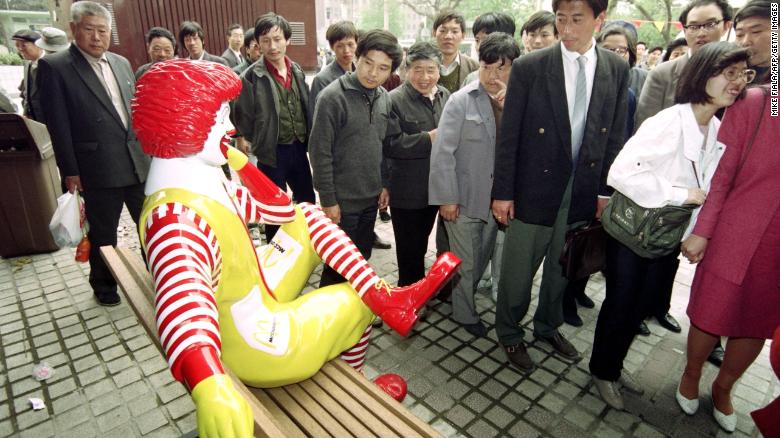 Passers-by keep their distance from Ronald McDonald as he sits outside the first McDonalds restaurant to be opened in Beijing on April 20, 1992.