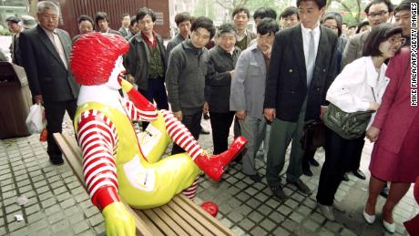 Passers-by keep their distance from Ronald McDonald as he sits outside the first McDonalds restaurant to be opened in Beijing on April 20, 1992.