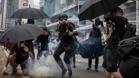 A pro-democracy protester throws a tear gas canister back at police amid clashes on Sunday.