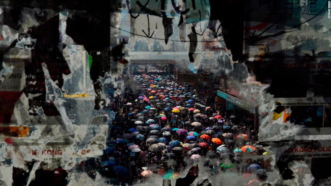 Marching anti-government protesters are seen through a window with peeled-off posters on October 1.