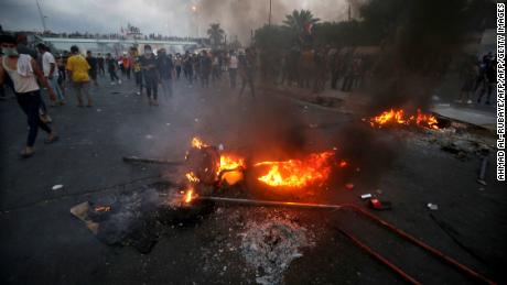 Iraqi protesters stand next to burning tyres during a demonstration in Baghdad on October 2, 2019.