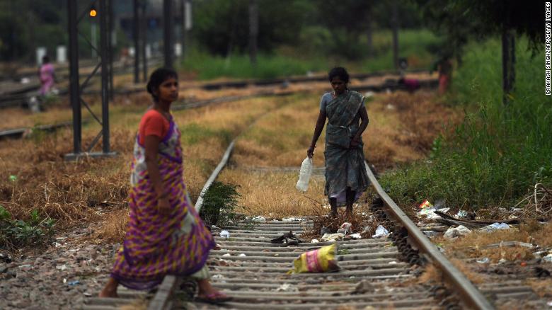 Women walking on train tracks in an area where people defecate in the open near Nizamuddin railway station in New Delhi on September 27, 2019.