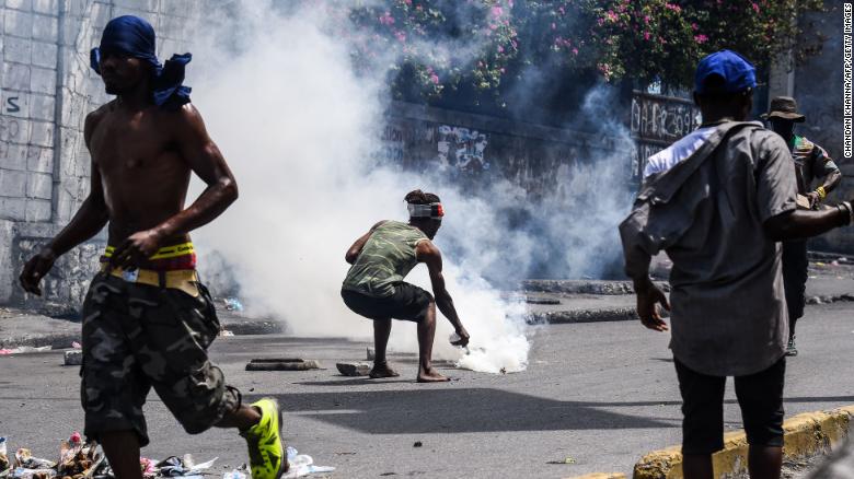 A demonstrator douses a tear gas canister with water during a protest demanding the resignation of President Jovenel Moise in Port-au-Prince on September 27, 2019.