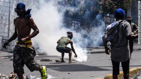 A demonstrator douses a tear gas canister with water during a protest demanding the resignation of President Jovenel Moise in Port-au-Prince on September 27, 2019.
