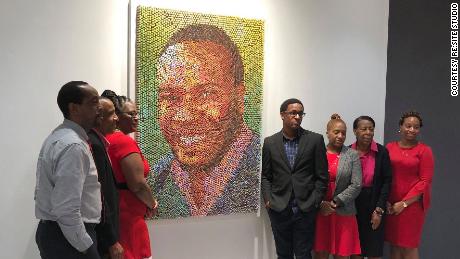 Members of Botham Jean&#39;s family pose with his portrait at PricewaterhouseCooper&#39;s Dallas office.