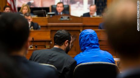 Syrian defector Caesar conceals his identity as he listens with a translator to the House Foreign Affairs Committee in 2014.