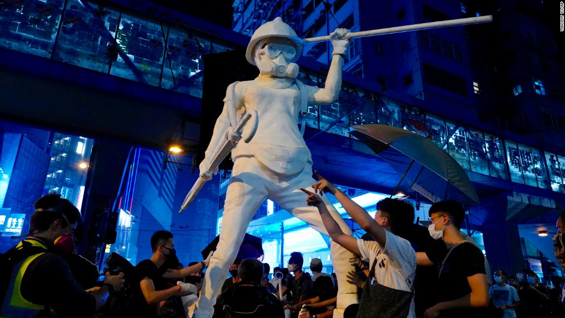 Protesters move a statue depicting a protester armed with gas mask, helmet and umbrella on the streets of Hong Kong on October 4.