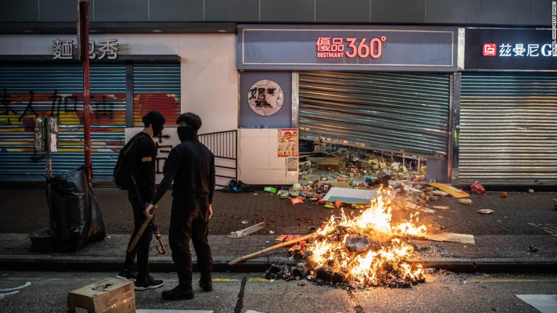 A fire is seen in front of a store vandalized by protesters.