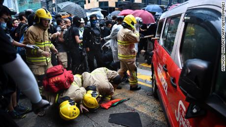 Rescue personnel check underneath a taxi after it hit two protesters along Cheung Sha Wan Road in Hong Kong on Sunday.