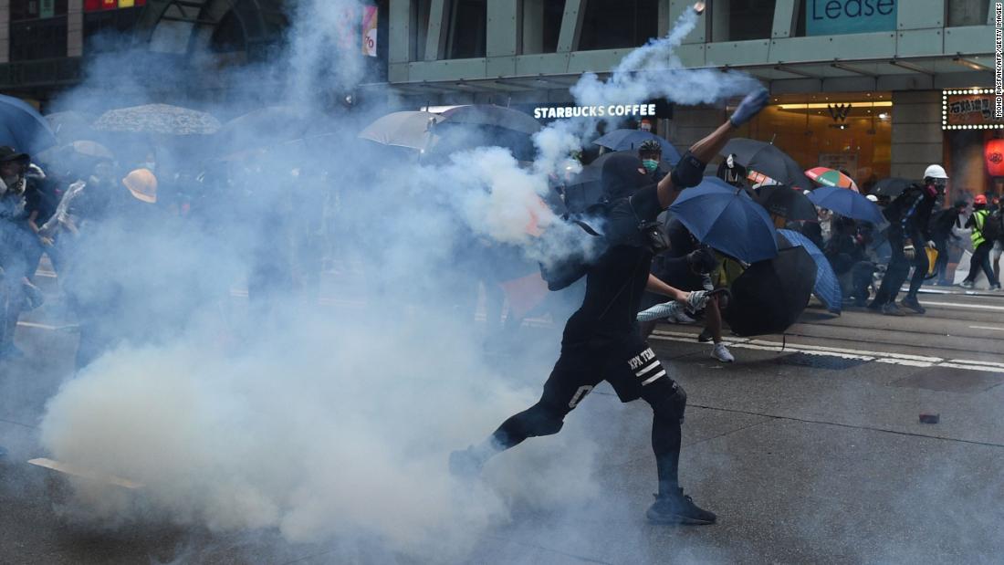 A protester throws a tear gas canister back toward police in Hong Kong on Sunday, October 6.