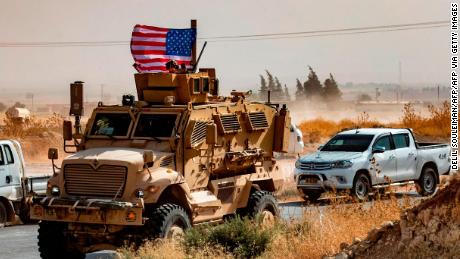 A US soldier sits atop an armoured vehicle during a demonstration by Syrian Kurds against Turkish threats next to a base for the US-led international coalition on the outskirts of Ras al-Ain town in Syria&#39;s Hasakeh province near the Turkish border on October 6, 2019. - US forces in Syria started pulling back today from Turkish border areas, opening the way for Ankara&#39;s threatened military invasion and heightening fears of a jihadist resurgence. (Photo by Delil SOULEIMAN / AFP) (Photo by DELIL SOULEIMAN/AFP via Getty Images)