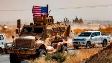 A US soldier sits atop an armoured vehicle during a demonstration by Syrian Kurds against Turkish threats next to a base for the US-led international coalition on the outskirts of Ras al-Ain town in Syria's Hasakeh province near the Turkish border on October 6, 2019. - US forces in Syria started pulling back today from Turkish border areas, opening the way for Ankara's threatened military invasion and heightening fears of a jihadist resurgence. (Photo by Delil SOULEIMAN / AFP) (Photo by DELIL SOULEIMAN/AFP via Getty Images)