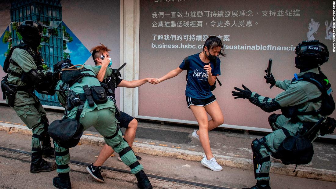 Police chase down a couple wearing facemasks in the central district in Hong Kong on October 5, 2019.