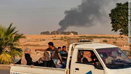 Civilians ride a pickup truck as smoke billows following Turkish bombardment on Syria's northeastern town of Ras al-Ain in the Hasakeh province along the Turkish border on October 9, 2019. - Turkey launched an assault on Kurdish forces in northern Syria with air strikes and explosions reported along the border. President Recep Tayyip Erdogan announced the start of the attack on Twitter, labelling it "Operation Peace Spring". (Photo by Delil SOULEIMAN / AFP) (Photo by DELIL SOULEIMAN/AFP via Getty Images)