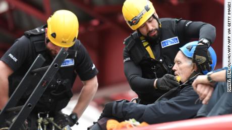 Police prepare to remove a climate change activist from the roof of a DLR train at Canary Wharf station.