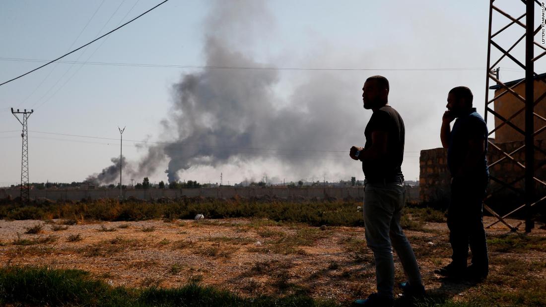 People in Akcakale, Turkey, watch smoke billow from inside Syria.