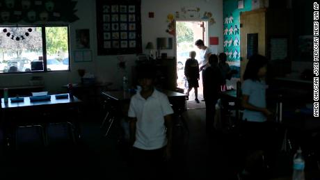 Students walk back into class after a recess at a school in San Jose, California. They relied on sunlight after a Pacific Gas &amp; Electric power shutdown turned out the lights. 