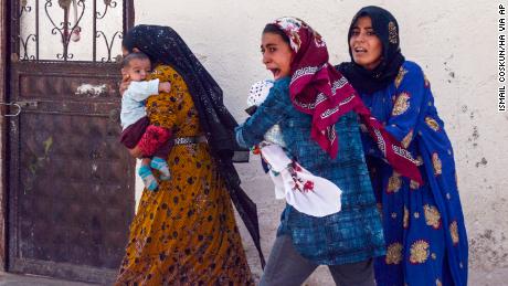 People run to take cover after mortars fired from Syria, in Akcakale, Turkey, Thursday, Oct. 10, 2019. An Associated Press journalist said at least two government buildings were hit by the mortars in Sanliurfa province&#39;s border town of Akcakale and at least two people were wounded.( Ismail Coskun/HA via AP )