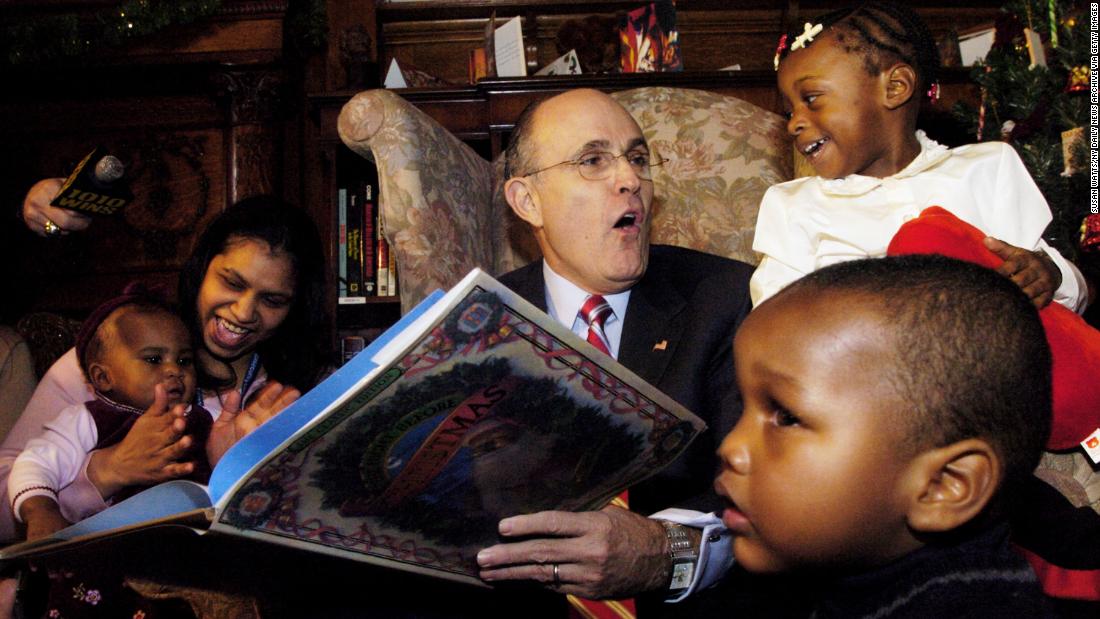 Giuliani reads &quot;The Night Before Christmas&quot; to children while visiting an orphanage in New York in December 2004.
