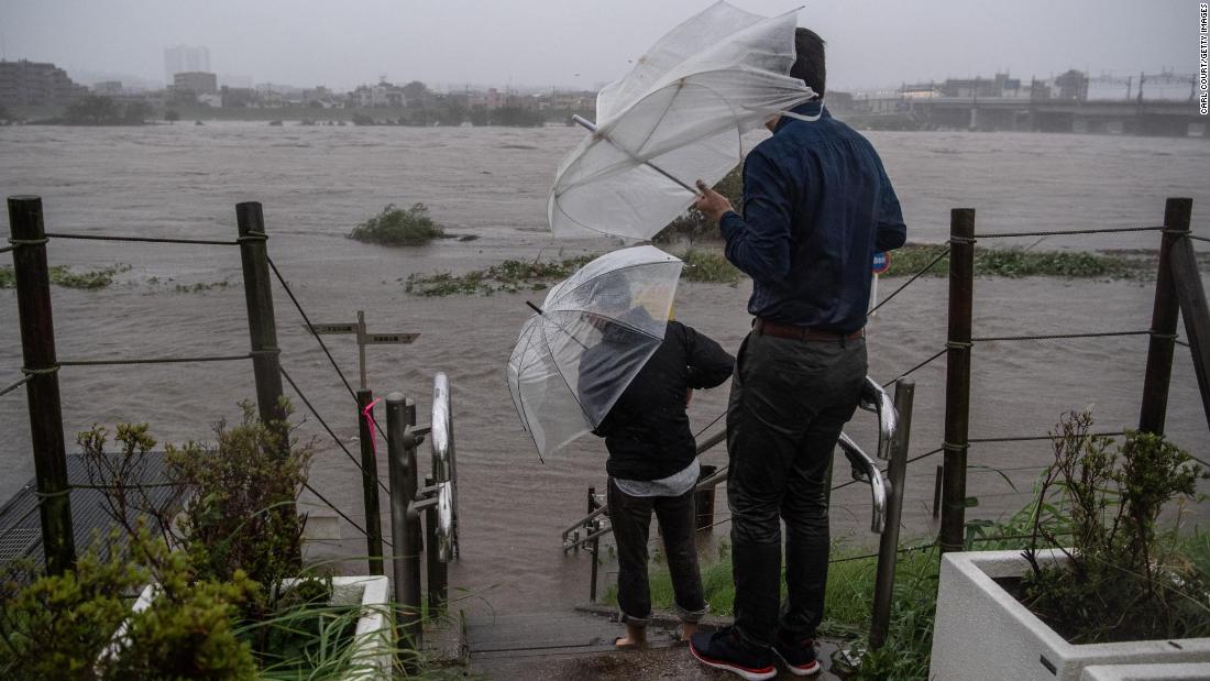 People look at the flooded Tama River in Tokyo on October 12.