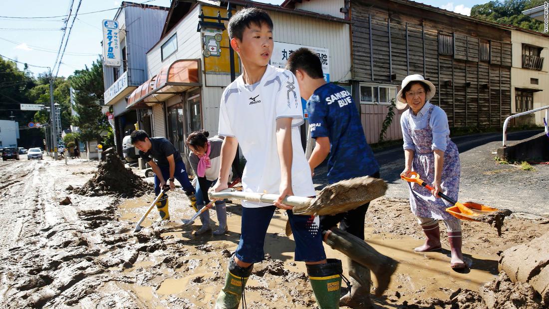 Students and residents scoop dirt and mud on October 13 as the town of Marumori, Japan, is flooded from the typhoon, which made landfall on Saturday.