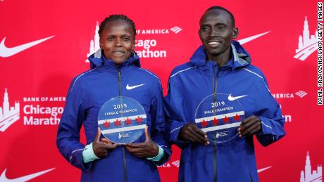 Kenya&#39;s Brigid Kosgei, left, and Lawrence Cherono smile as they hold their trophies. 