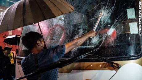 HONG KONG, CHINA - OCTOBER 13: A pro-democracy protester attempts to break a tourist bus front windows in Mongkok district on October 13, 2019 in Hong Kong, China. Hong Kong&#39;s government invoked emergency powers last week to introduce an anti-mask law which bans people from wearing masks at public assemblies as the city remains on edge with the anti-government movement entering its fourth month. Protesters in Hong Kong continue to call for Chief Executive Carrie Lam to meet their remaining demands since the controversial extradition bill was withdrawn, which includes an independent inquiry into police brutality, the retraction of the word riot to describe the rallies, and genuine universal suffrage, as the territory faces a leadership crisis.