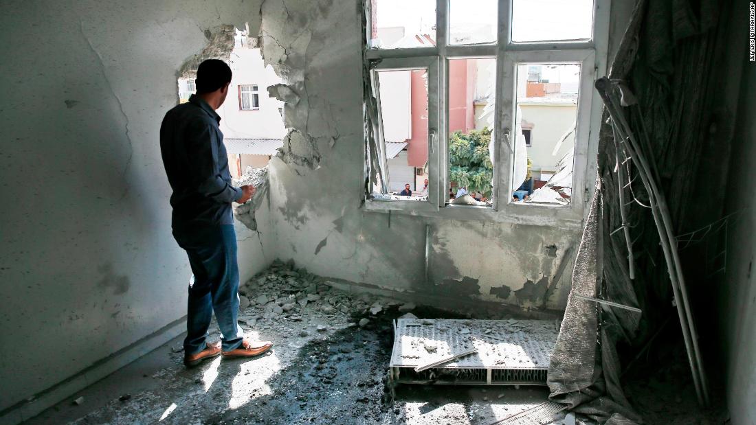A person inspects damage to a building in Akcakale, Turkey, on Sunday, October 13. The building was damaged by a mortar fired from inside Syria.