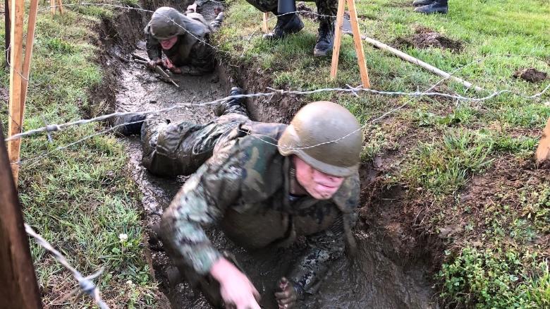 US Naval Academy plebes crawl under barbed wire and through mud during Sea Trials.