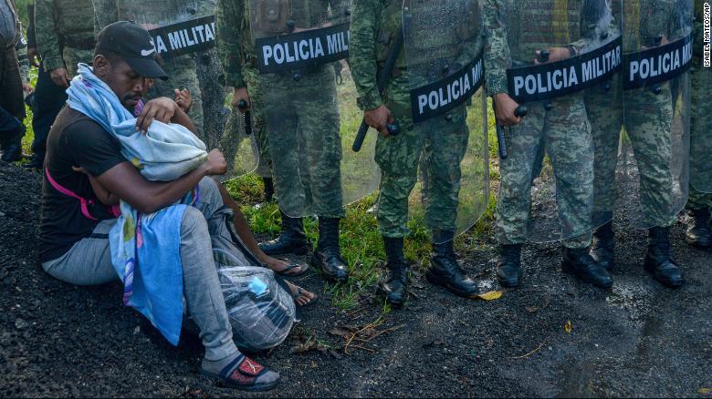 A migrant tends to a child while surrounded by members of the National Guard near Tuzantan, Mexico, on October 12.