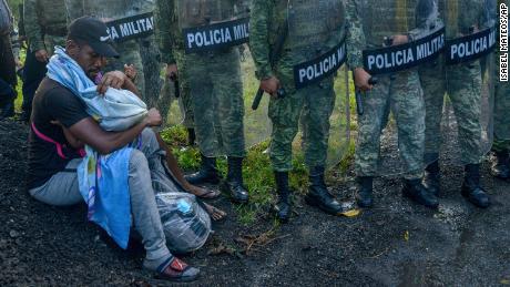 A migrant tends to a child while surrounded by members of the National Guard near Tuzantan, Mexico, on October 12.