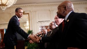 President Barack Obama, left, reaches across to shakes hands with Rep. Elijah E. Cummings, D-Md., right, after signing HR 4348, the Surface Transportation Bill, during a ceremony in the East Room of the White House in Washington, Friday, July 6, 2012. 