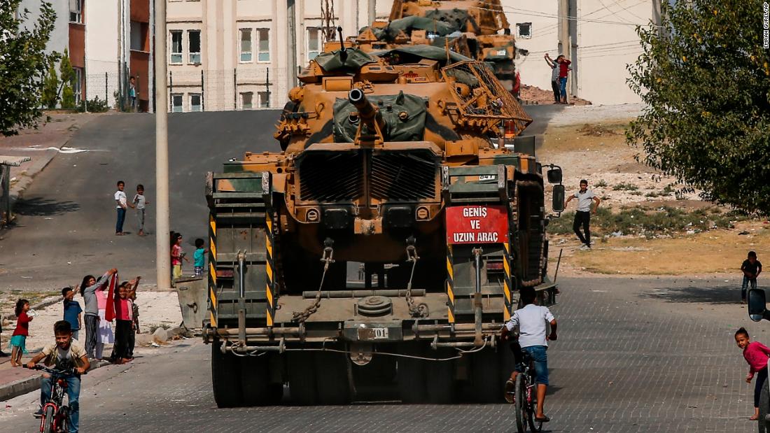 Local residents cheer as Turkish army tanks are transported on the outskirts of Akcakale, Turkey, on October 17.