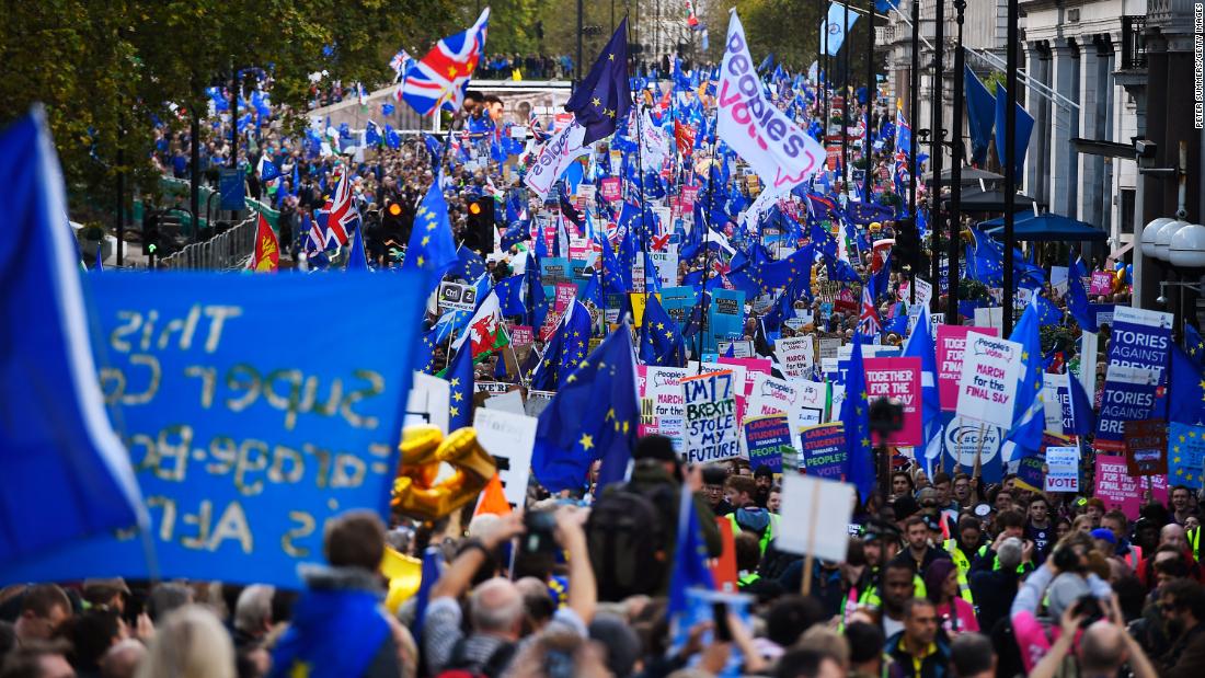 Crowds march through central London holding European Union flags and anti-Brexit signs. 