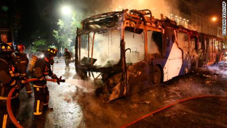 Firefighters put out the flames on a burning bus during a protest in Santiago, Friday, October 18, 2019. 