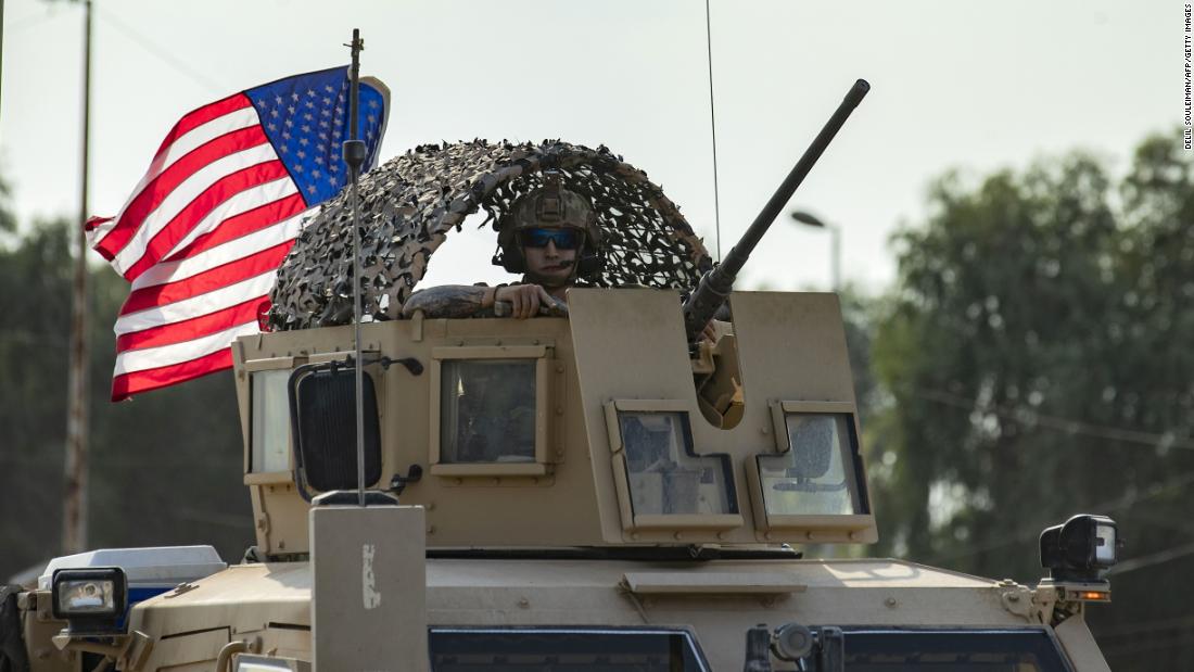 A US service member looks out of an armored vehicle as troops pull out of their base in Tal Tamr.